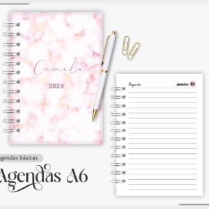 Agenda espiral com capa marmorizada rosa, caneta branca e página interna pautada aberta.
