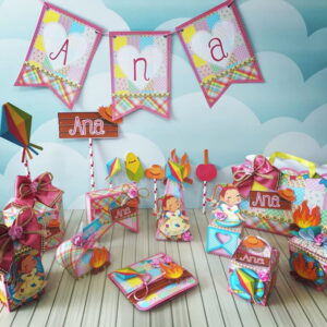 Arquivo de Corte Festa Junina Arraia Menina Digital 16 Decoração de festa temática colorida com bandeirinhas e caixas personalizadas sobre mesa.