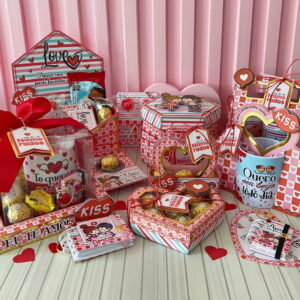 Diversas embalagens decoradas com corações, laços vermelhos, doces e canecas em uma mesa.