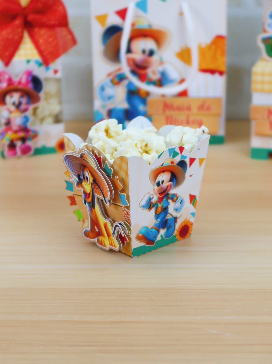 Arraiá da Turma do Mickey Studio para Festa Junina 2 Caixa de papel personalizada com personagens e pipoca sobre superfície de madeira.