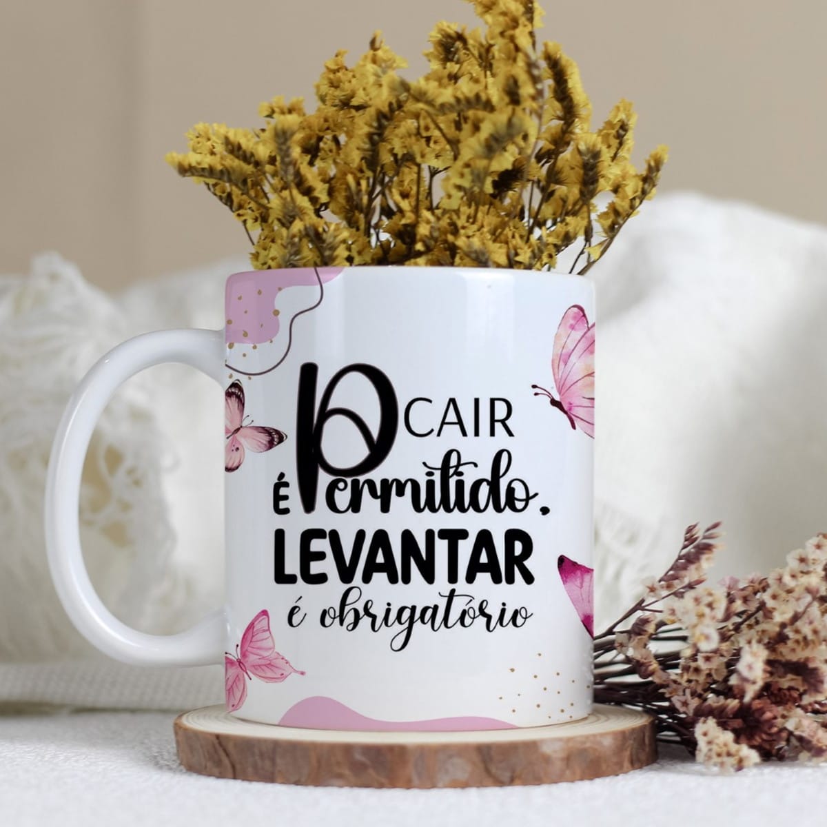 Arte Digital Borboletas e Frases para Canecas 2 Caneca branca com frase motivacional e estampas de borboletas cor-de-rosa, contendo flores secas amarelas.