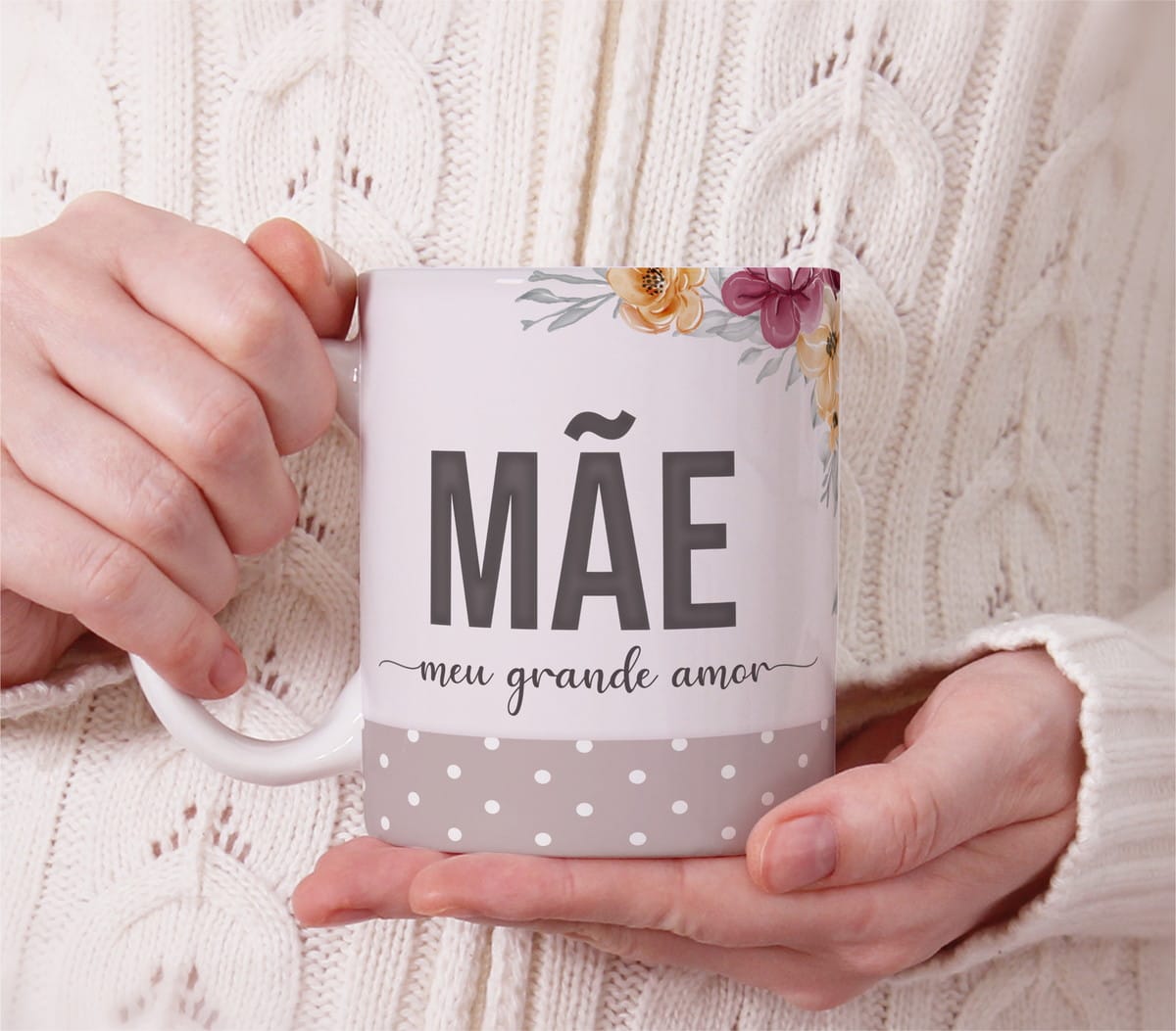 Arte Digital Caneca Mãe para Sublimação PNG PDF CDR 1 Pessoa com blusa de lã branca segura caneca decorada com flores e texto.