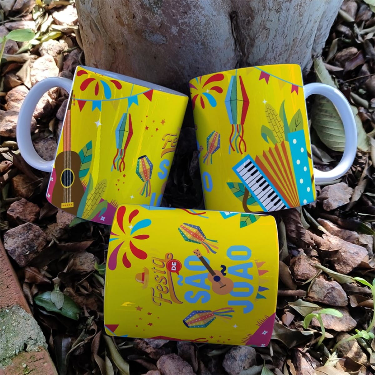 Artes Digitais Festa Junina para Caneca JPG e Corel 3 Três canecas amarelas com estampa temática de festa junina sobre solo de pedras.