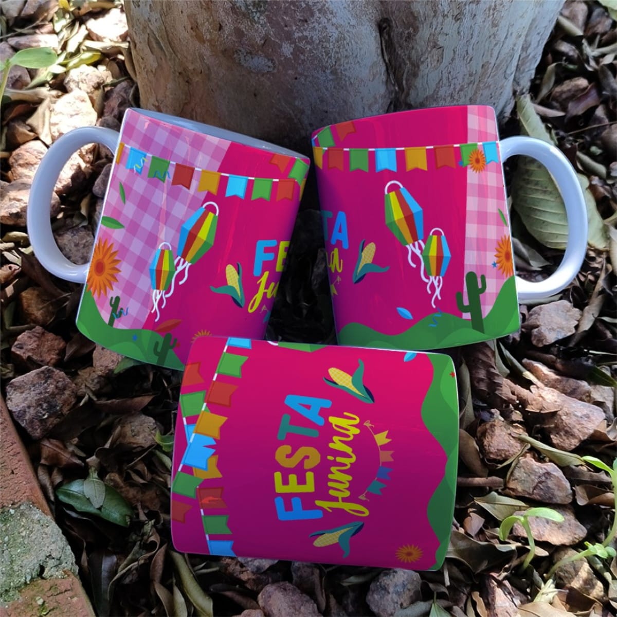 Artes Digitais Festa Junina para Caneca JPG e Corel 5 Três canecas brancas com estampa colorida sobre pedras em solo de terra.