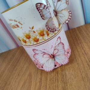 Artes para Tubo de Lata Dia das Mães PDF PNG 14 Copo decorado com estampas de flores e borboletas sobre mesa de madeira