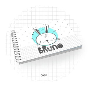 Caderno espiral com ilustração de coelho e nome sobre fundo quadriculado cinza.