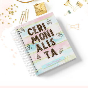 Caderno Digital Cerimonialista para Agendas Encantadoras 6 Caderno espiral colorido com capa decorada cercado por pequenos clipes dourados na mesa branca