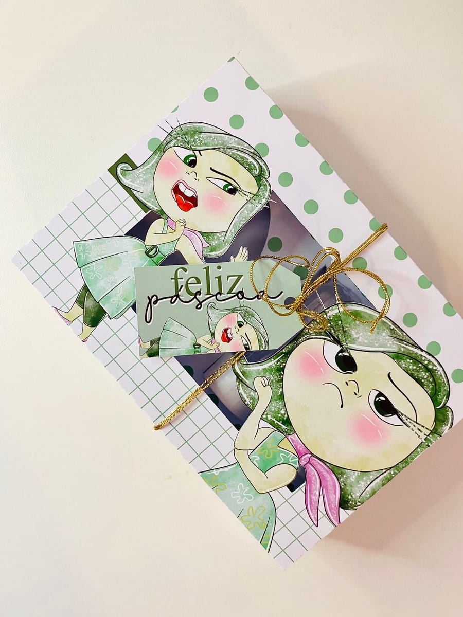 Caixa Mini Confeiteiro Divertidamente Páscoa Digital PDF 2 Caixa decorada com personagem de cabelo verde e etiqueta de Feliz Páscoa anexada.