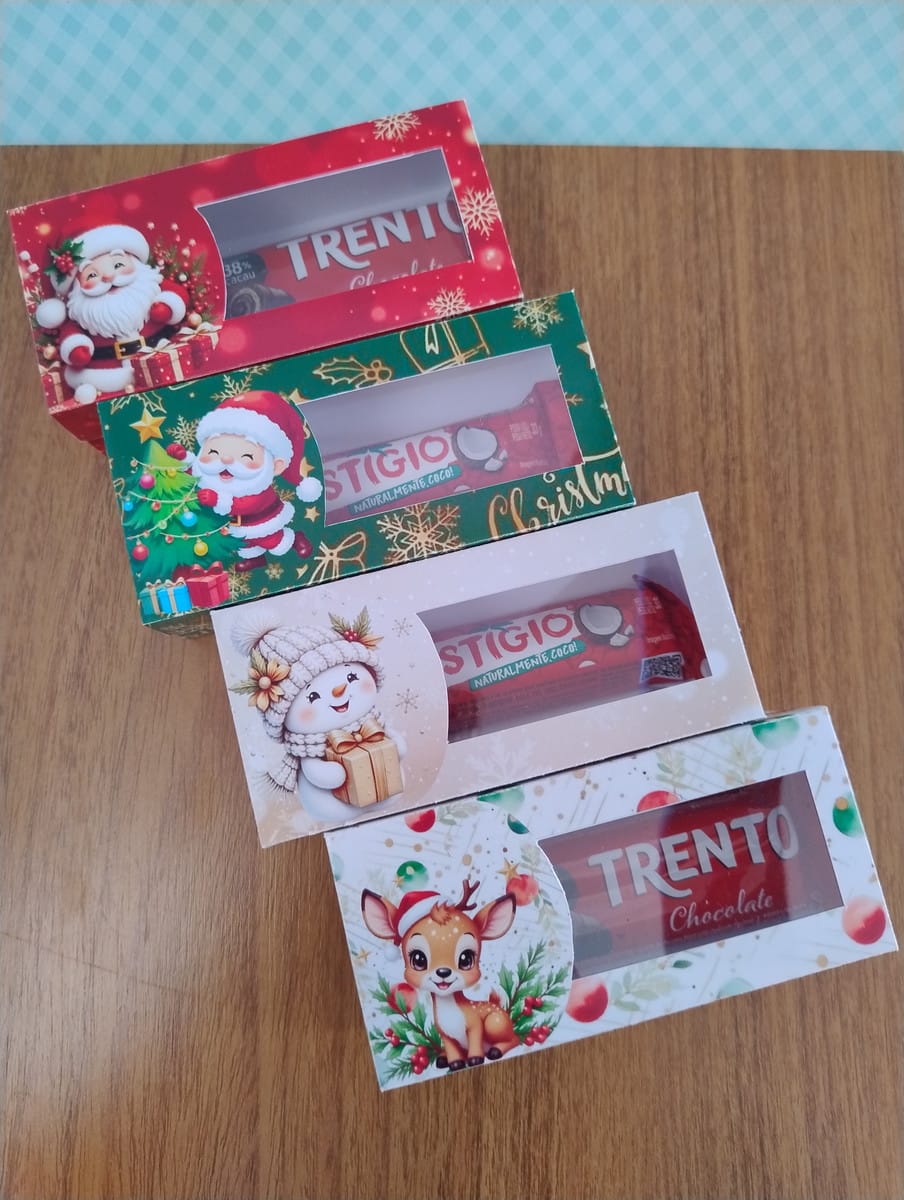 Caixinhas de Natal Vintage em PNG e PDF 4 Quatro caixas de doces decoradas com temas natalinos sobre uma mesa de madeira.