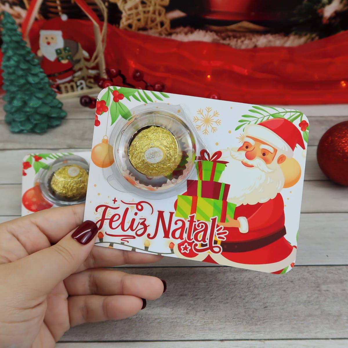 Card Blister Natal 2023 Digital para Embalagens Festivas 4 Mão segurando suporte decorativo com bombom em ambiente natalino