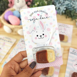 Mão segurando embalagem decorada de Páscoa com coelho e doce de chocolate.