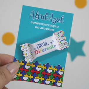 Card e Balas Autismo Arquivo Digital para Imprimir 12 Mão segurando arte digital de cartão azul com tema de autismo.