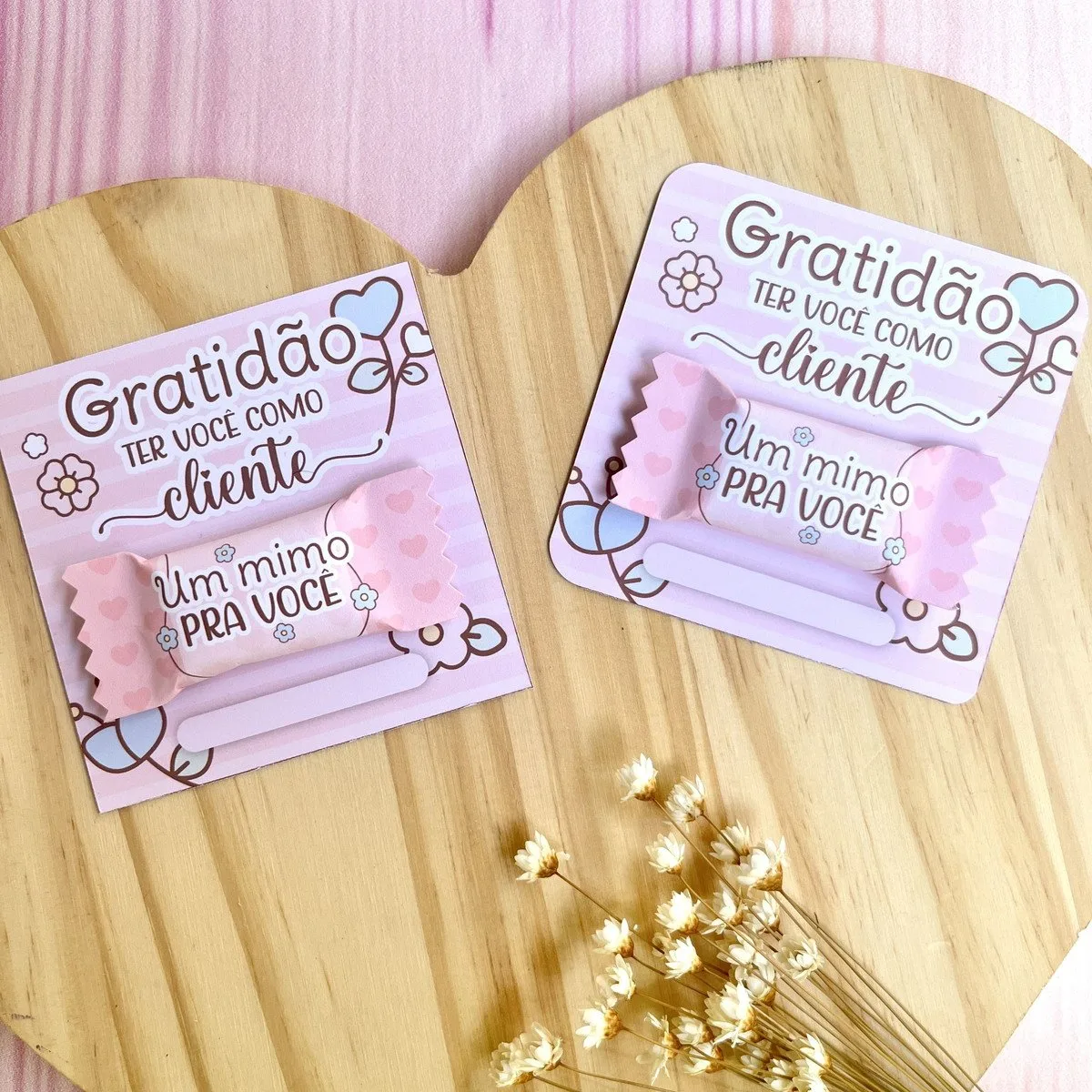 Card e Balinha Mimos Clientes 3 Dois cartões personalizados com doces presos sobre uma superfície de madeira clara.