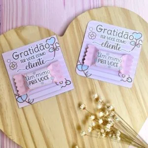 Dois cartões personalizados com doces embalados sobre base de madeira circular com flores secas.