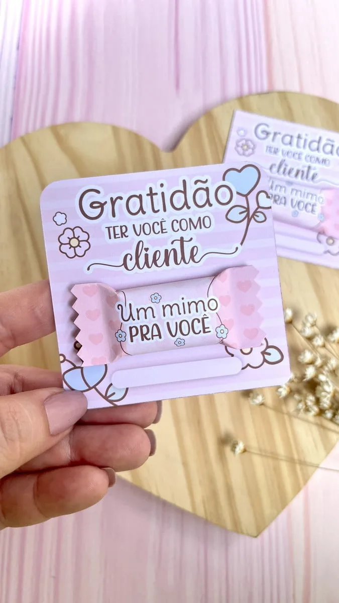 Card e Balinha Mimos Clientes 4 Mão segurando cartão com bala personalizada com tema de agradecimento ao cliente.