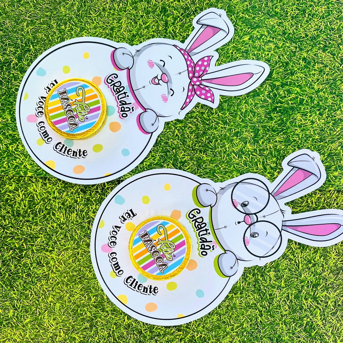 Card Moedinha de Páscoa Digital para Imprimir 3 Dois cartões circulares com coelhos de papel sobre grama artificial verde.