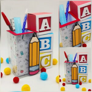 Porta-lápis temático escolar decorado com blocos de alfabeto e desenhos de lápis.