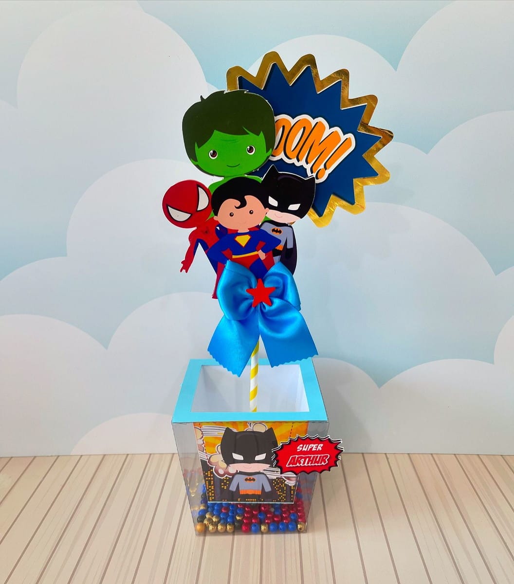 Centro de Mesa Super Heróis Editável PDF e Studio 1 Arte digital para centro de mesa com ilustrações de super-heróis e balão 'BOOM!'.