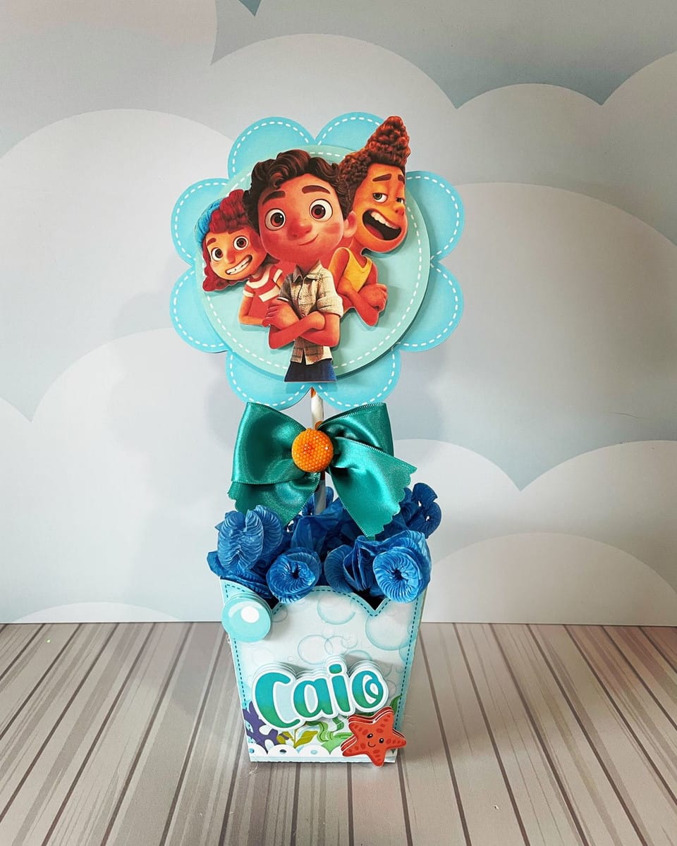 Centro de Mesa Luca Digital para Festa Infantil 1 Enfeite de mesa azul com três personagens infantis e um laço decorativo.