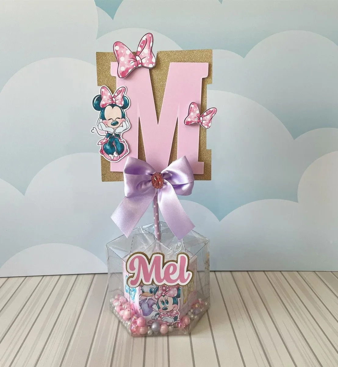 Centro de Mesa Minnie Acetato 1 Decoração de mesa personalizada com letra M, laço lilás e personagem infantil.