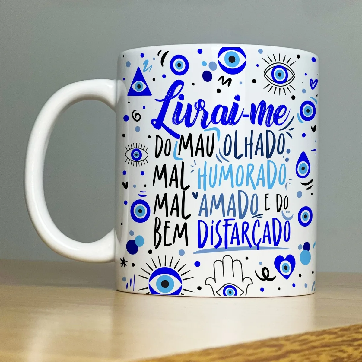 Estampa Caneca Livrai-me do Mau Olhado e do Bem Disfarçado 1 Caneca branca estampada com símbolos de olho grego e frases em letras azuis