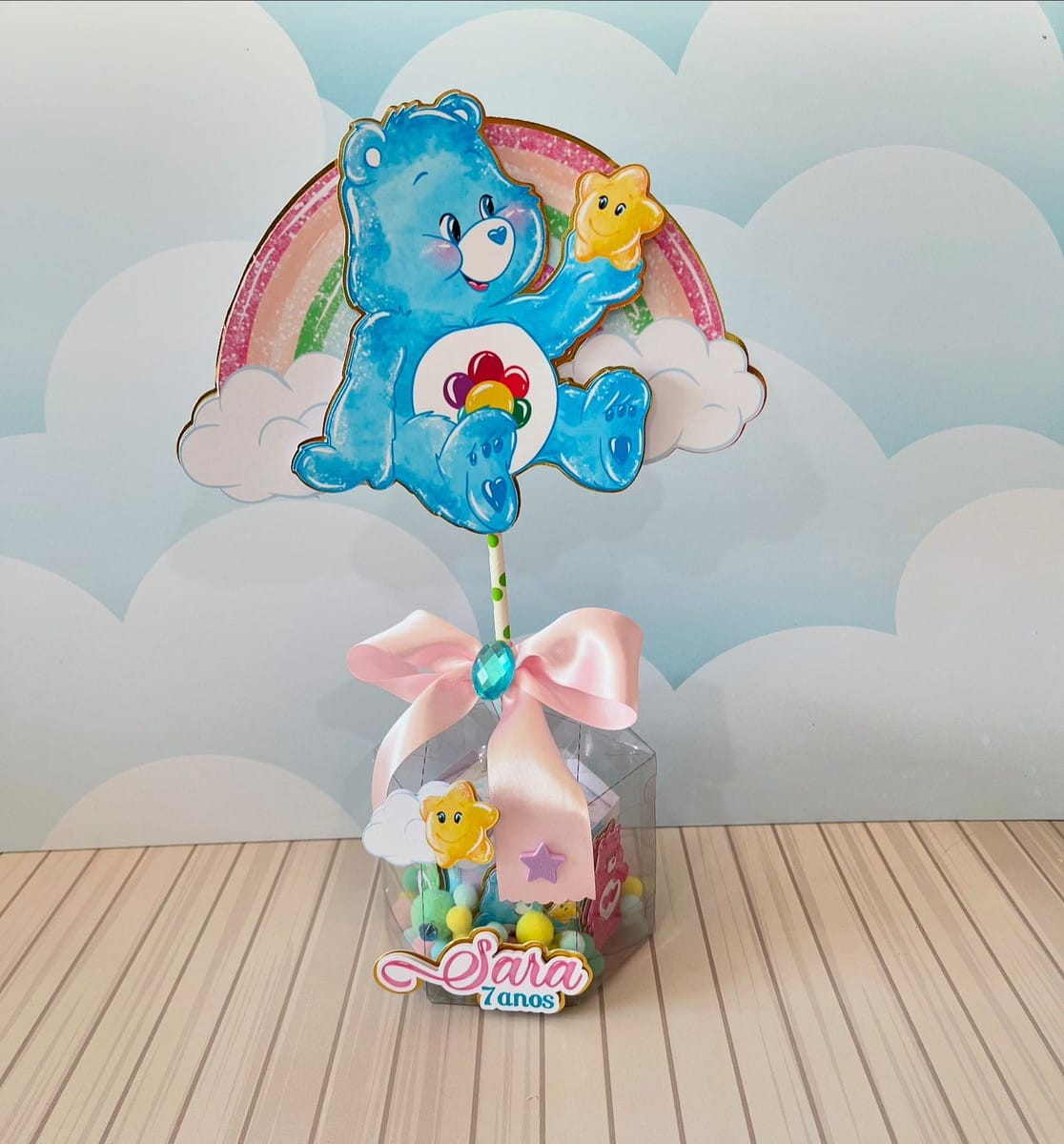 Festa Ursinhos Carinhosos Luxo Kit Digital Studio e PDF 2 Urso azul em arco-íris e nuvens, decorando caixa transparente com doces coloridos.
