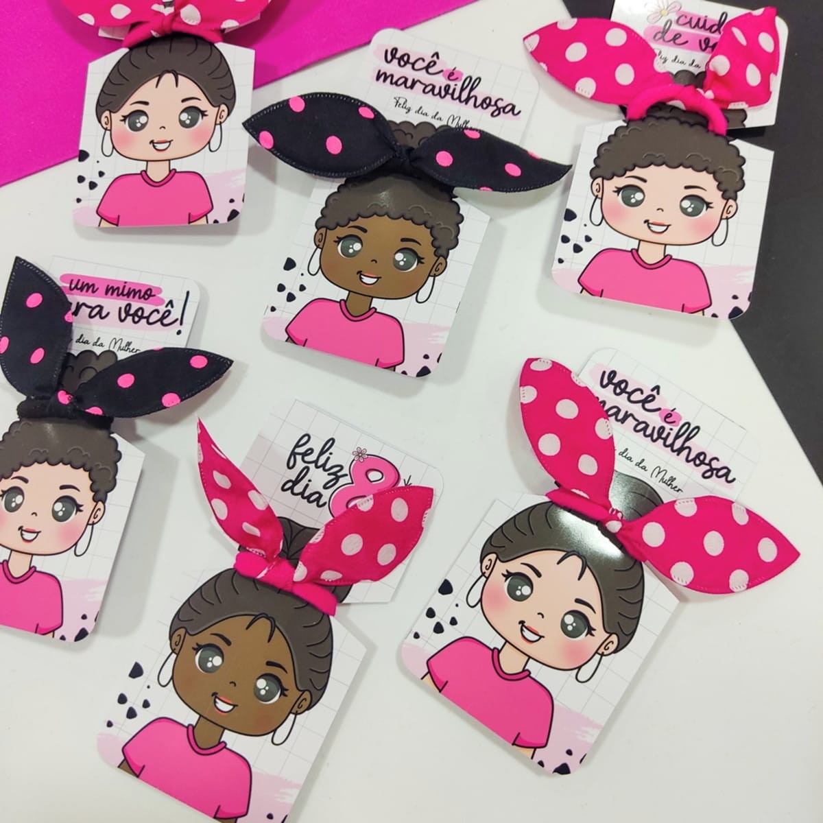 Kit Artes Dia da Mulher com 239 Arquivos em PNG e PDF 3 Vários cartões ilustrados com laços de cabelo coloridos e estampados dispostos em superfície branca