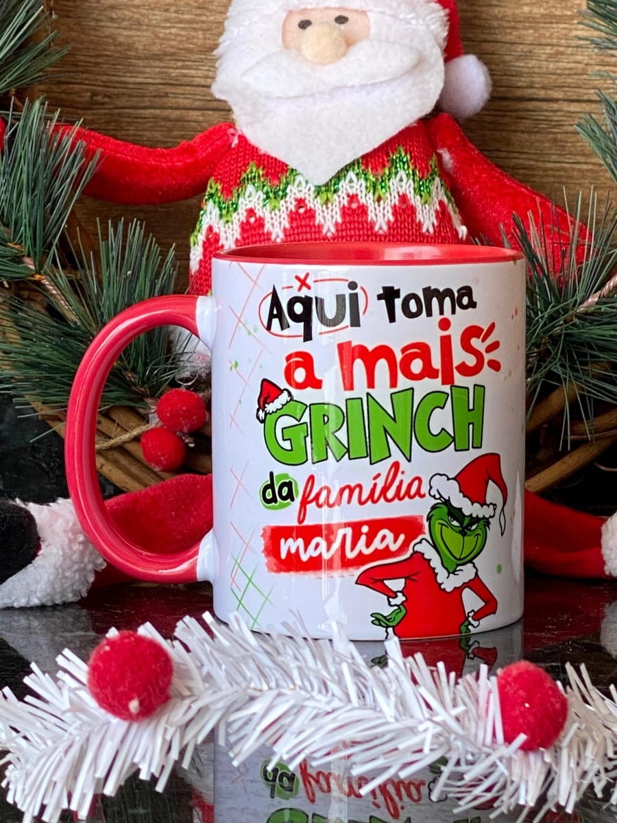 Kit Artes Grinch Debochado para Canecas em PNG e PSD 2 Caneca branca com estampa temática de natal e boneco do papai noel ao fundo.