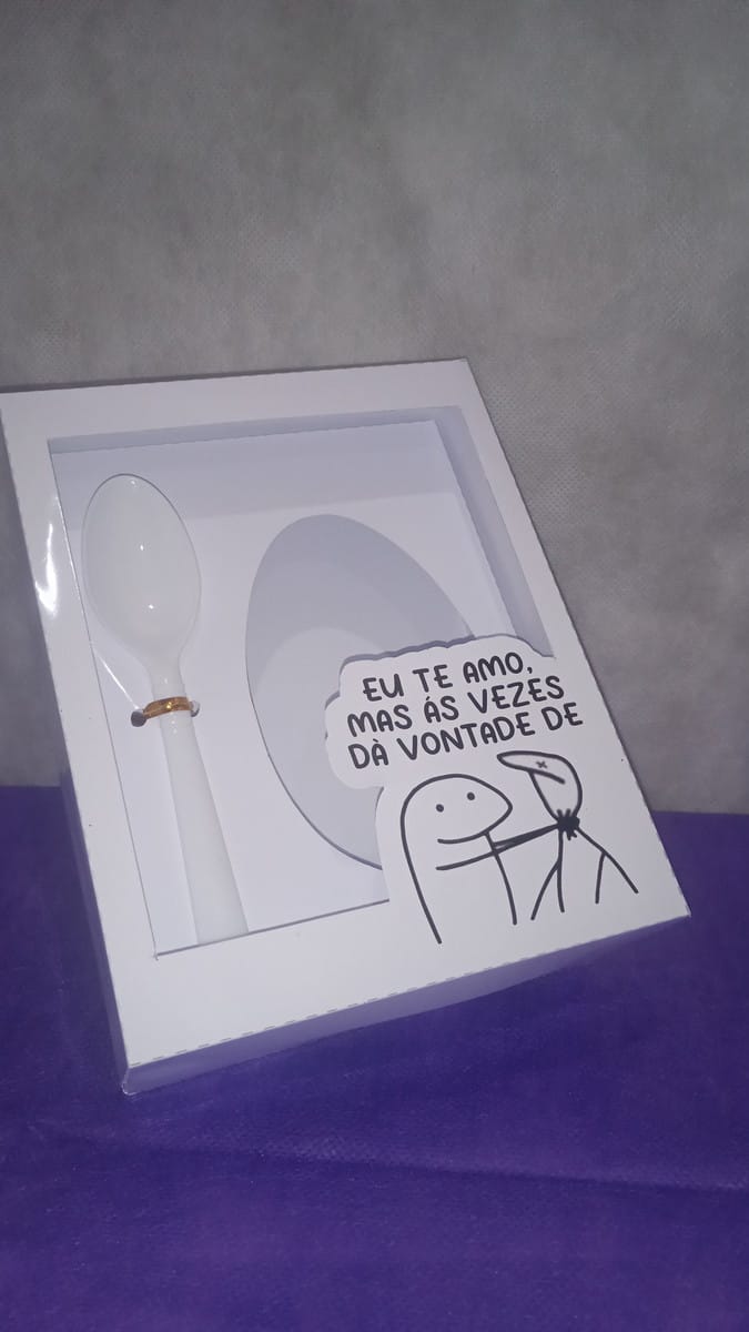 Kit Caixa Ovo de Colher Flork Arquivo Digital para Imprimir 4 Caixa branca decorada com colher e adesivo de desenho humorístico sobre fundo roxo.