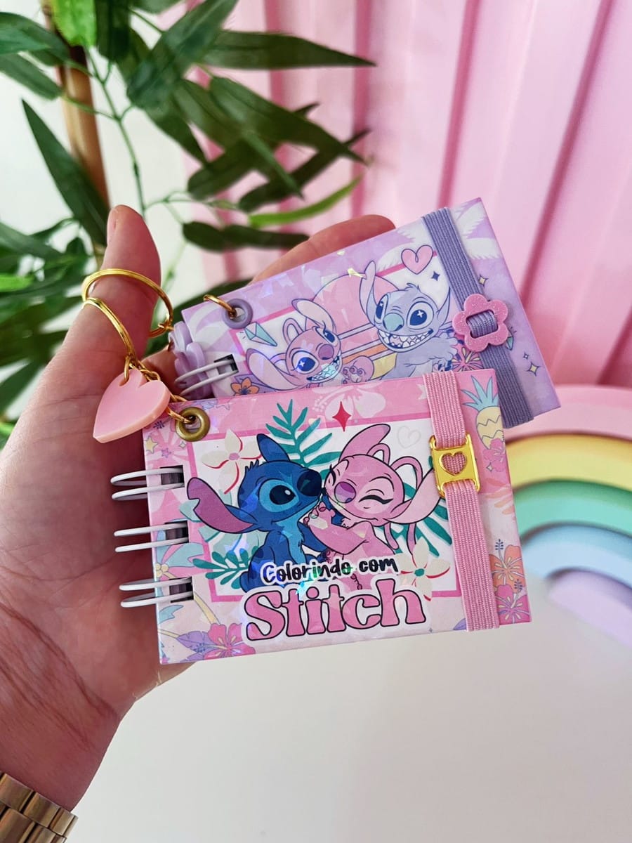 Kit Colorir Stitch Mini Digital para Projetos 3 Mão segurando dois pequenos cadernos temáticos ilustrados com personagens de desenhos animados coloridos.