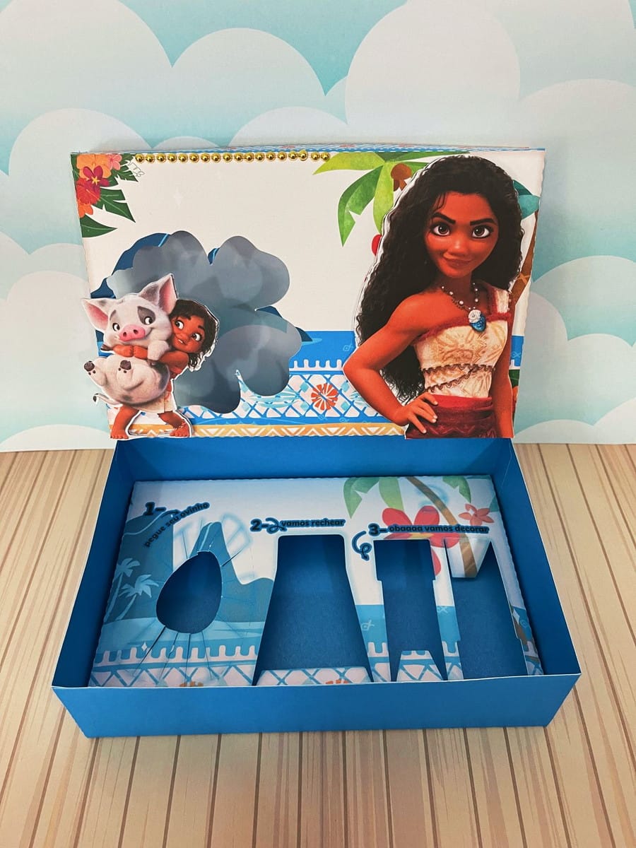 Kit Confeiteiro Moana Caixa Decorativa para Doces 2 Caixa azul temática aberta com ilustrações de personagem feminina e porquinho, exibindo compartimentos vazios.