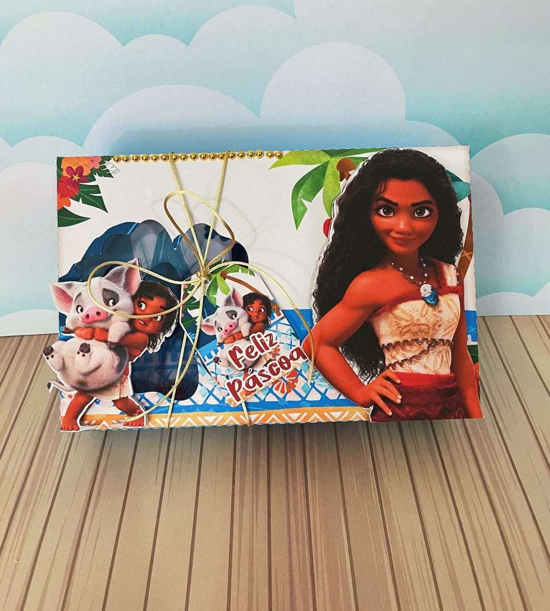 Kit Confeiteiro Moana Caixa Decorativa para Doces 5 Caixa decorada com personagem de pele morena e porquinho sobre fundo tropical com fita.