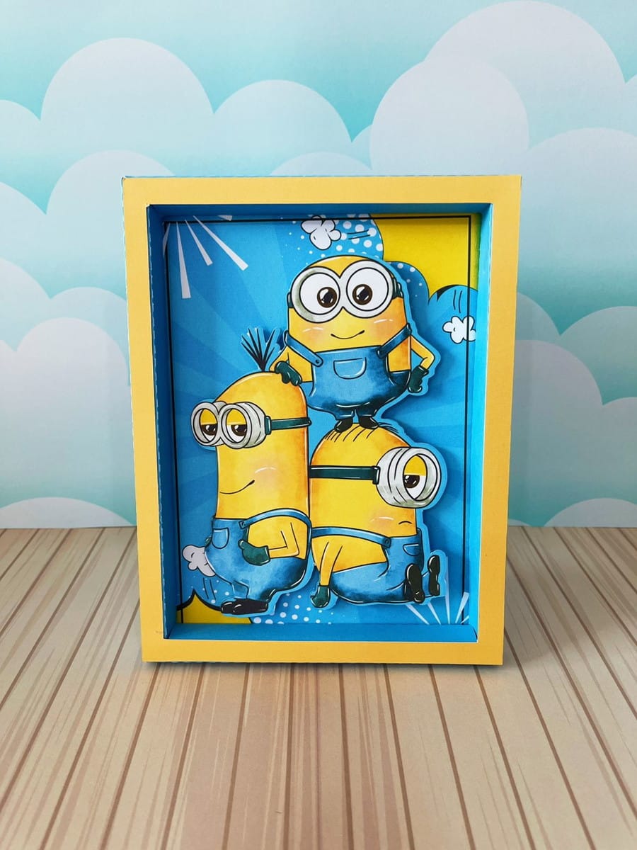 Kit Digital Festa Minions Luxo para Corte e Impressão 5 Quadro com três figuras amarelas em camadas sobre um fundo azul com nuvens.