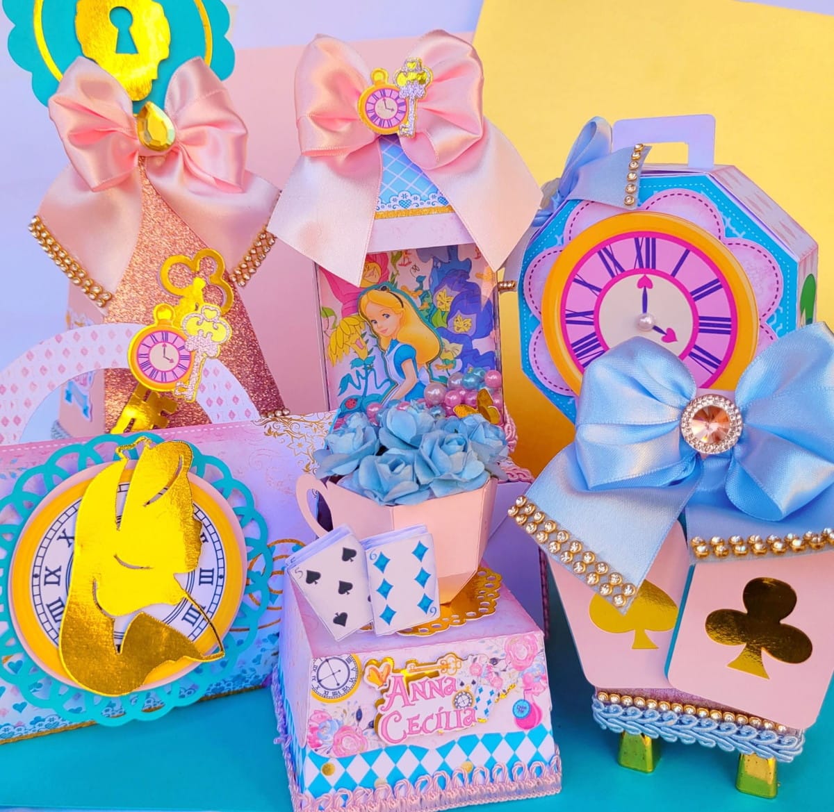 Kit Festa Alice no País das Maravilhas Luxo PDF e Studio 1 Caixinhas decoradas coloridas com laços de fita e ilustrações temáticas em fundo colorido.