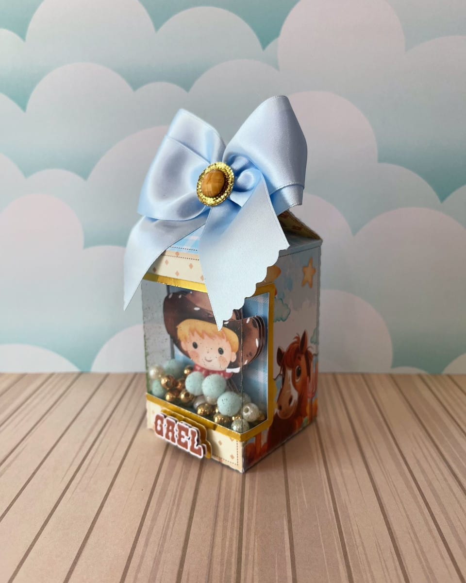 Kit Festa Cowboy Menino Studio e PDF para Personalizar 4 Caixa personalizada de papel com laço azul e visor contendo pequenas esferas decorativas internas.
