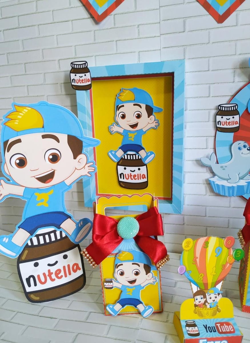 Kit Festa Digital Luccas Neto e Gi para Imprimir 5 Decorações de festa infantil com personagem de boné azul, potes Nutella e selo.