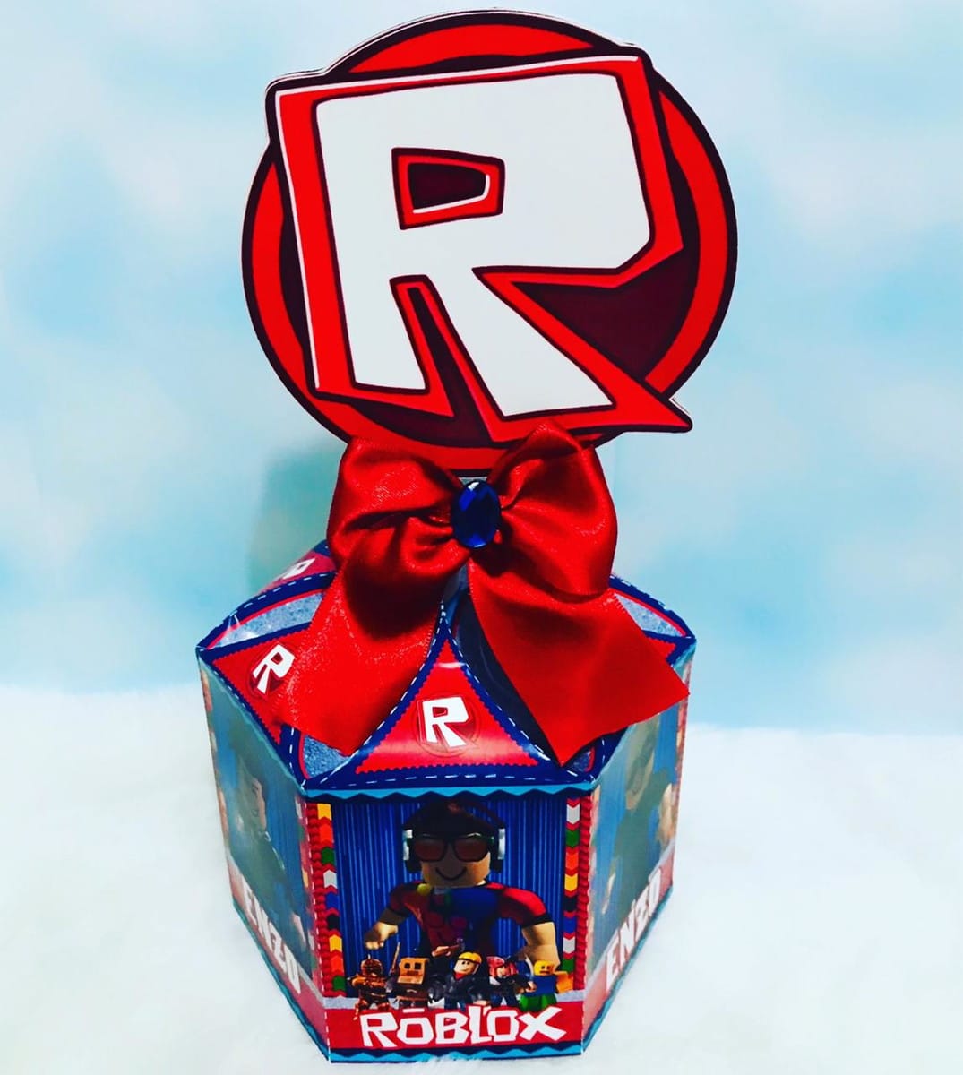 Kit Festa Roblox Editável com Moldes para Imprimir 5 Caixa decorativa hexagonal com laço vermelho, logo "R" e a palavra "Roblox".