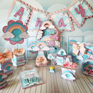 Kit de festa com tema de arco-íris, nuvens e bandeirinhas coloridas em papelaria.