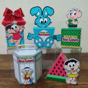 Kit Festa Turma da Monica Studio Artes Vetoriais para Corte 4 Conjunto de caixas decoradas com personagens de desenho animado sobre uma mesa.