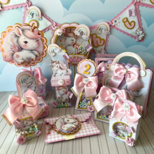 Kit de lembrancinhas de festa com tema de unicórnio, laços rosas e caixas personalizadas.