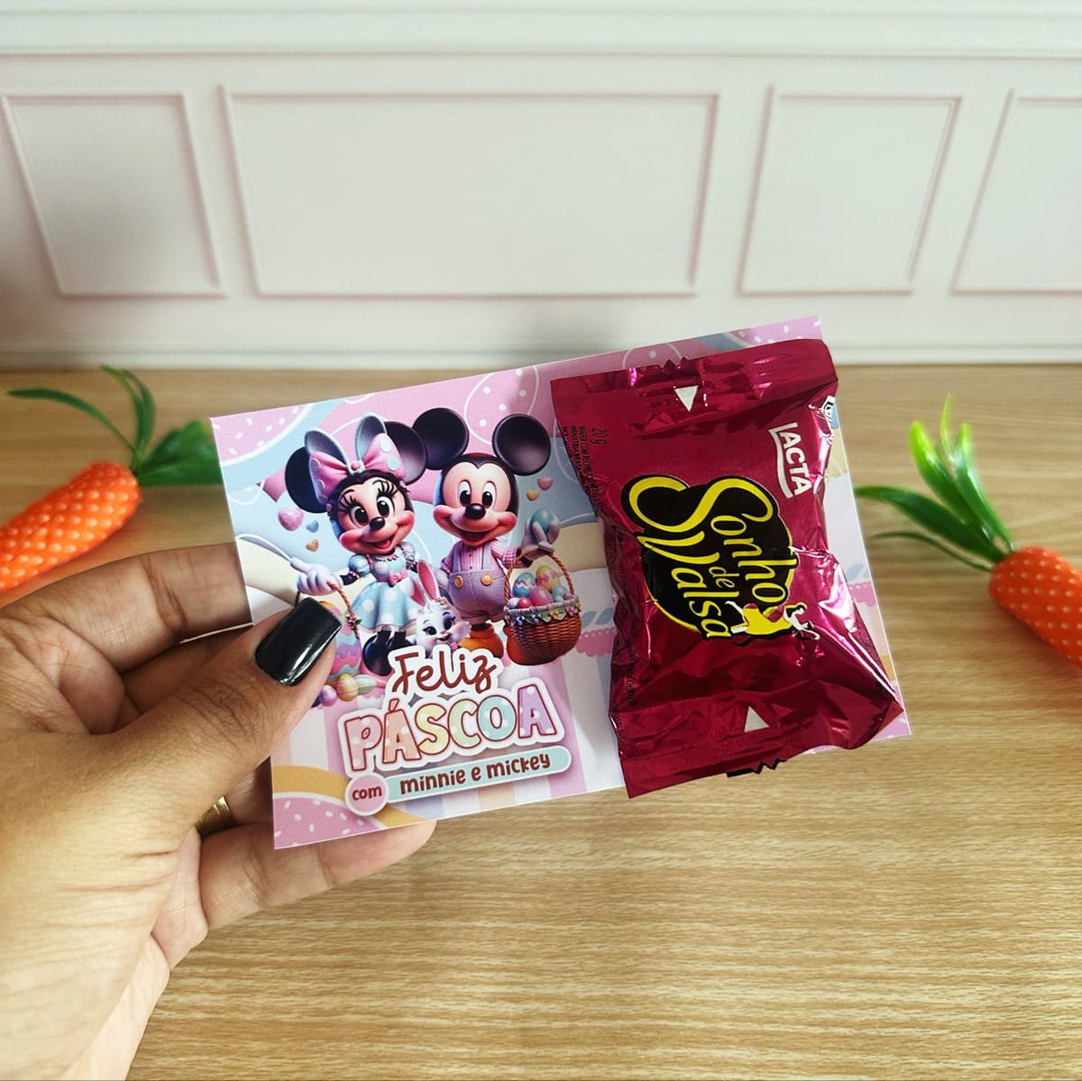 Kit Mimos de Páscoa Minnie e Mickey Digital 3 Mão segurando cartão temático de Páscoa com um chocolate anexado.