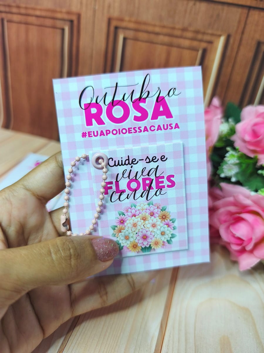 Kit Mimos Outubro Rosa 2025 Digital para Lembrancinhas 5 Mão segurando cartão temático rosa com frase e chaveiro pendurado.