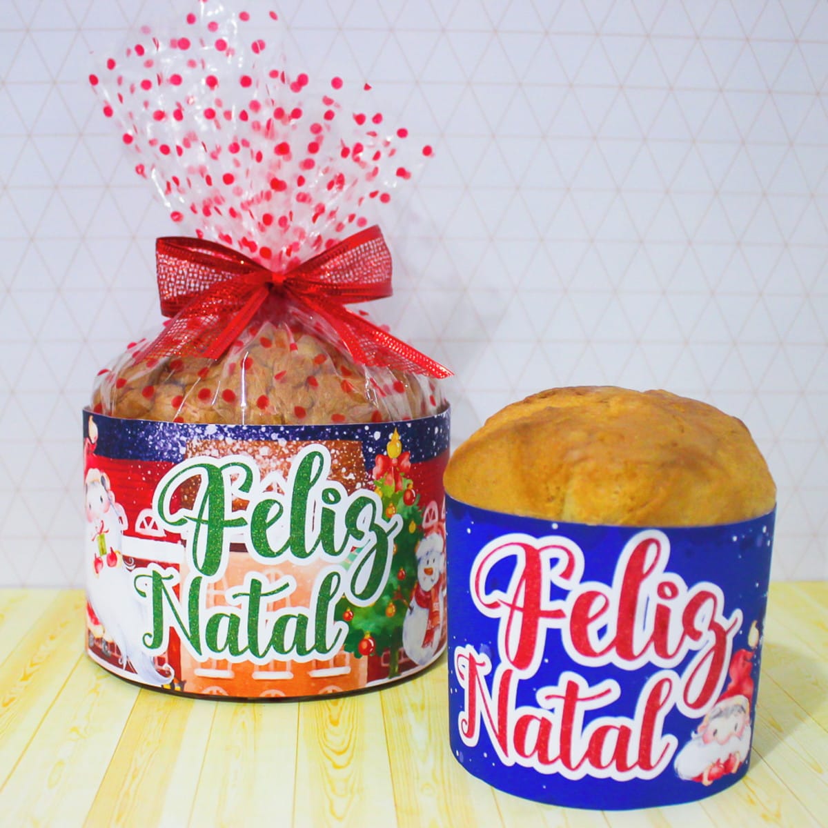 Kit Natal Aquarela Digital com Embalagens para Doces 3 Dois panetones decorados com embalagens coloridas de Natal sobre uma mesa amarela.