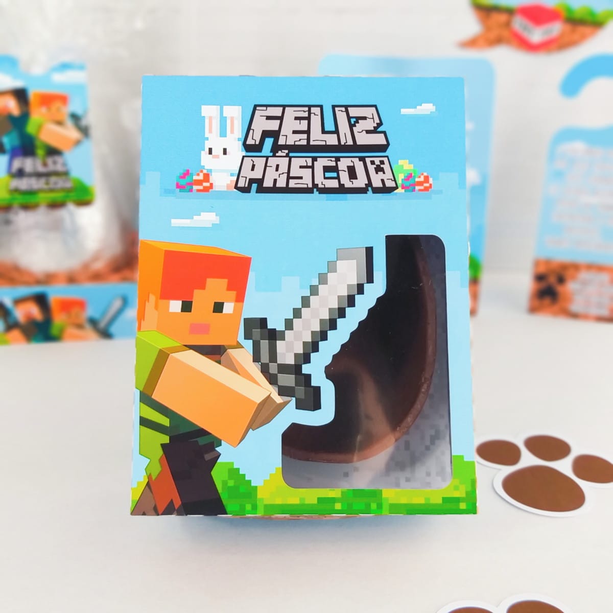 Kit Páscoa Minecraft Arquivo Digital para Confeiteiros 3 Caixa azul decorada com personagem pixelado segurando espada e ovo de chocolate visível.