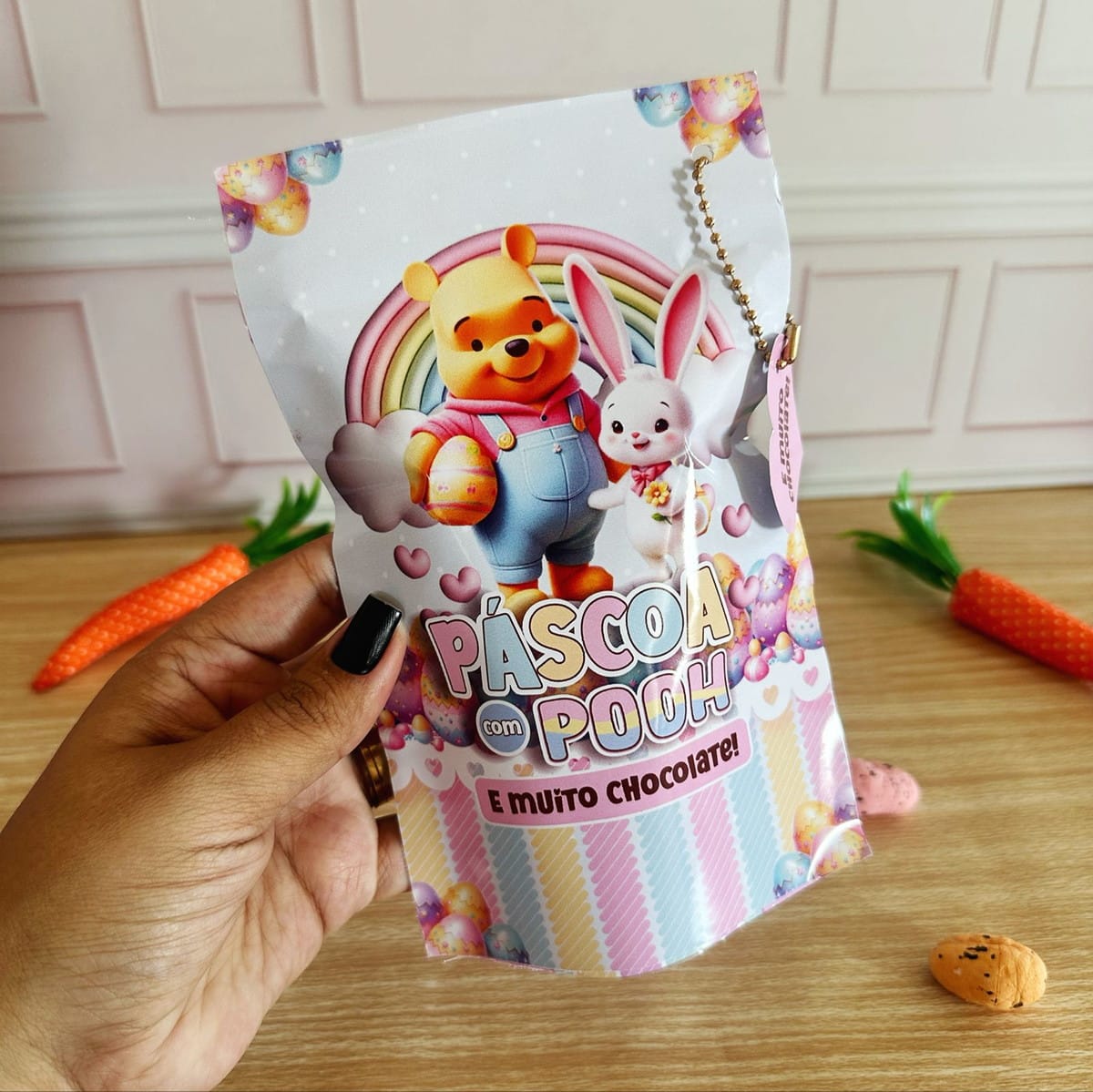 Kit Páscoa Ursinho Pooh Digital com Artes para Embalagens 2 Mão segurando embalagem temática de páscoa com urso e coelho estampados.