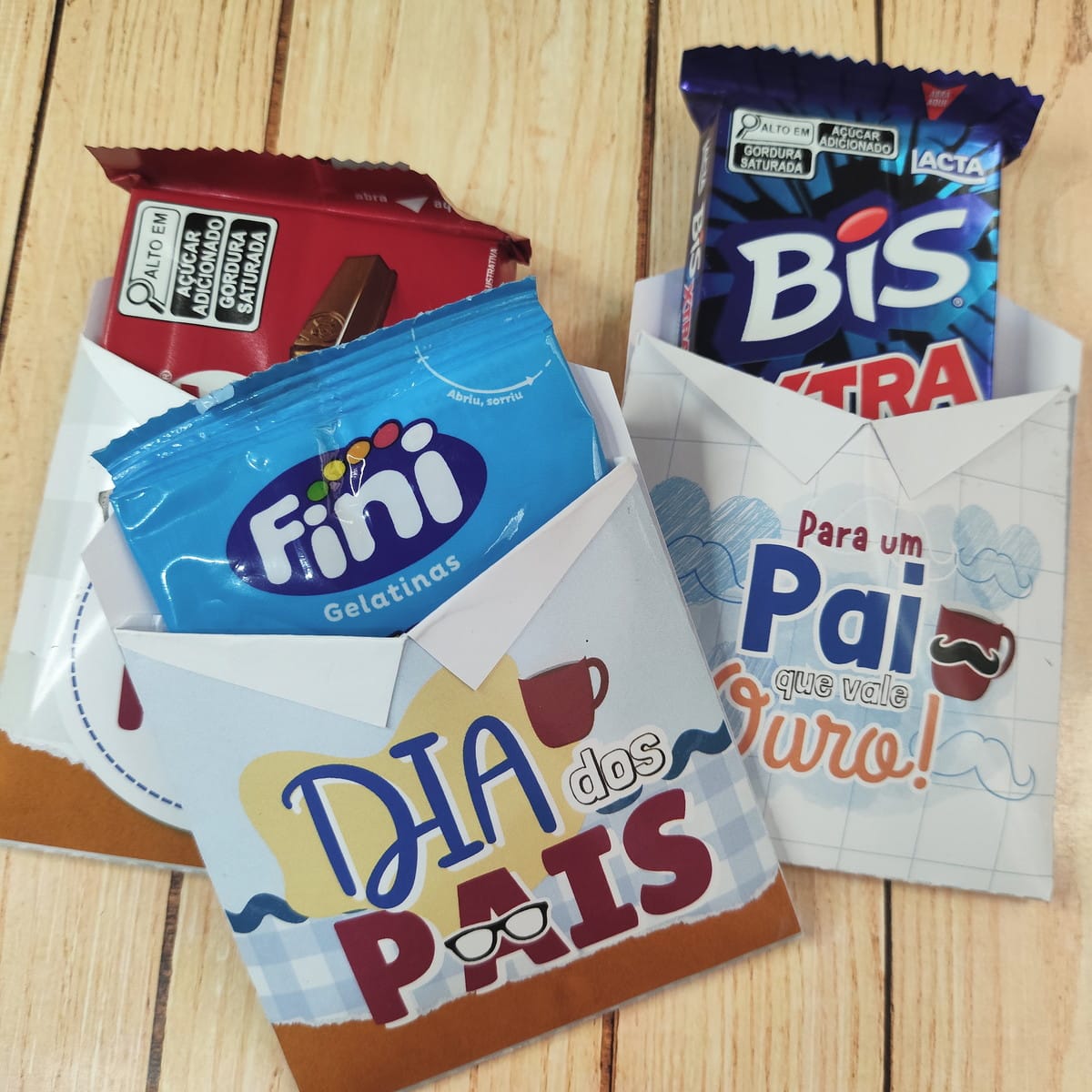 Lembrancinhas Dia dos Pais Religiosas PNG e PDF 4 Designs de envelopes temáticos para o Dia dos Pais, com doces variados dentro.