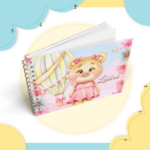 Caderno espiral ilustrado com ursa de vestido rosa e balão de ar quente.