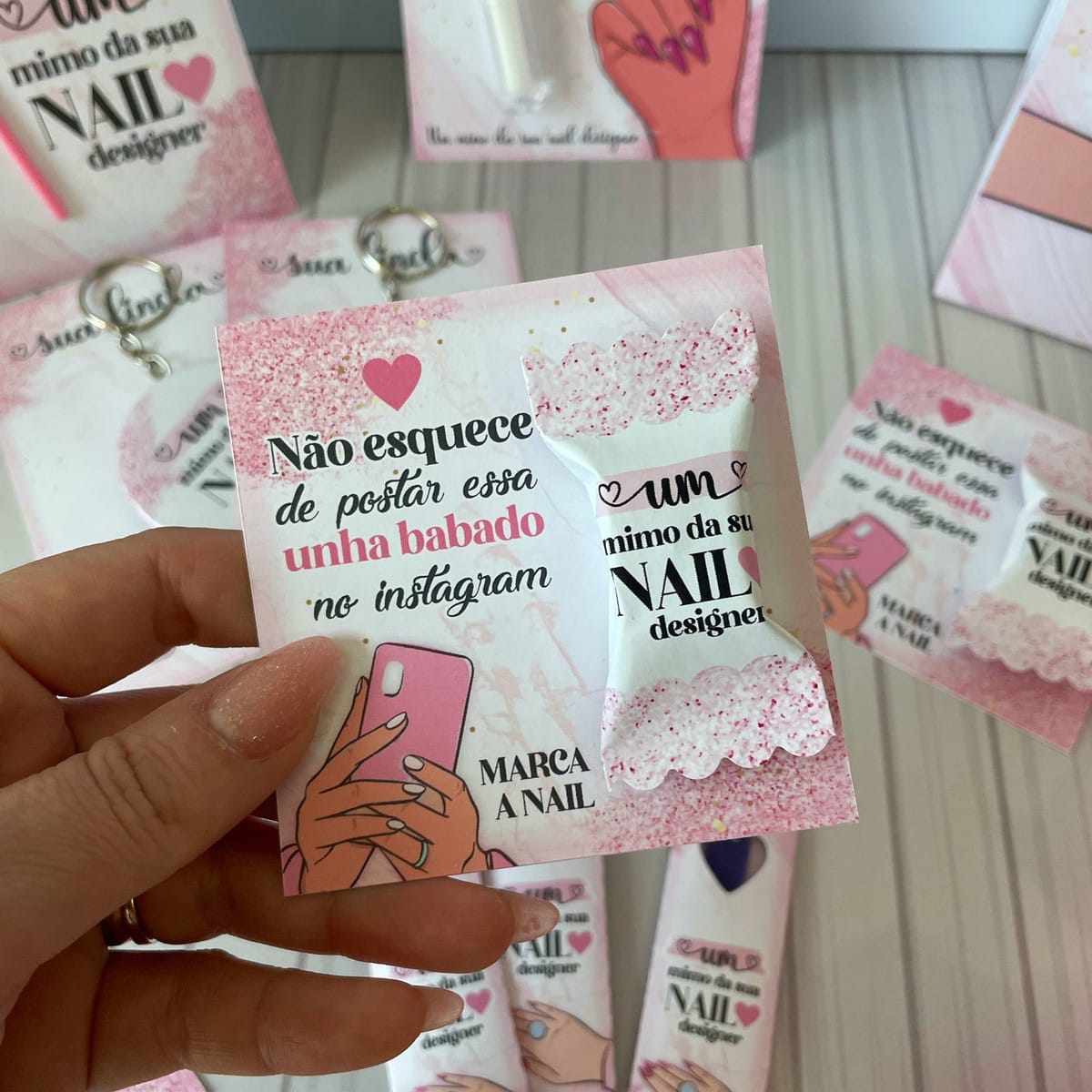 Mimos Nails Designer Arquivo Digital com Moldes de Corte 3 Mão segurando cartão rosa e branco com doces e frases impressas