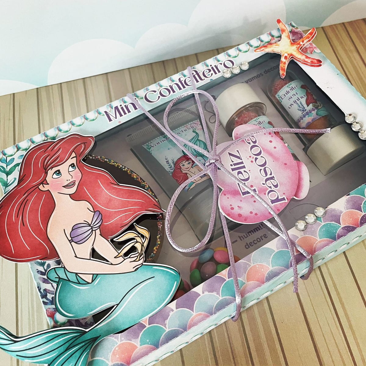 Mini Confeiteiro Ariel Arquivo Digital para Imprimir 4 Caixa decorada com tema de sereia contendo confeitos e fitas coloridas.