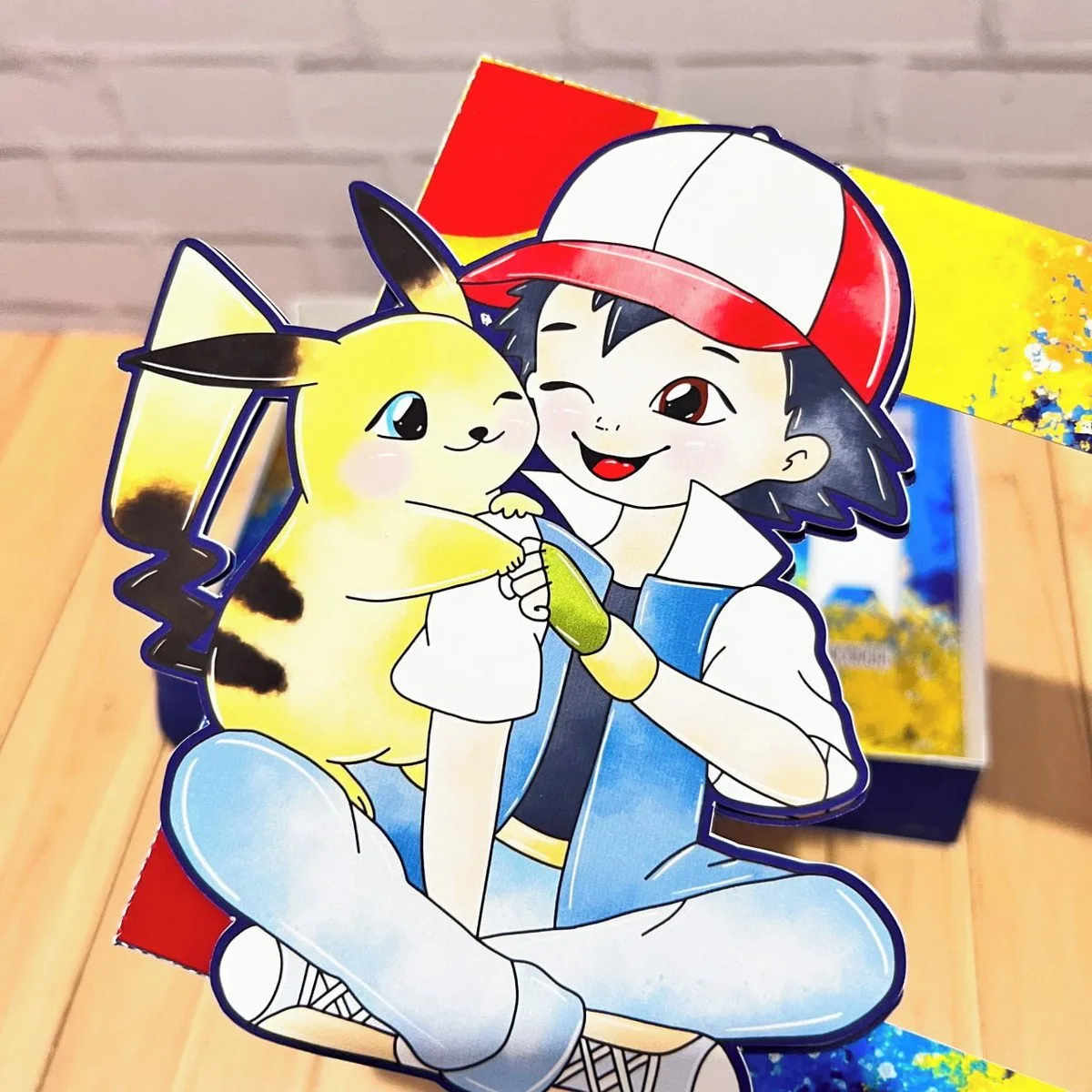 Mini Confeiteiro Páscoa Pokémon 3 Artesanato de papel com um personagem de anime e um ratinho amarelo abraçados.